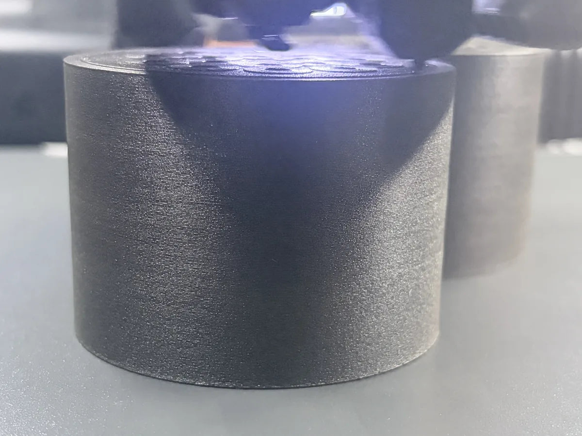	3D-Drucker druckt einen schwarzen Zylinder aus Kunststoff in Nahaufnahme